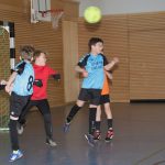 Jungen spielen Handball in der Sporthalle.