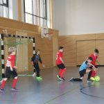 Kinder spielen in der Turnhalle Fußballspiel
