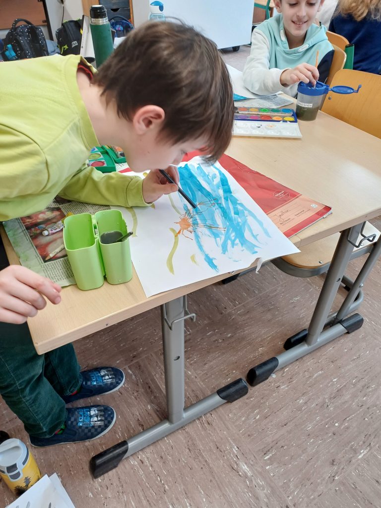 Kind malt mit Wasserfarben im Klassenzimmer.