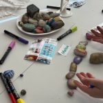 Person malt bunte Steine auf einem Tisch
