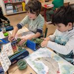 Kinder malen mit Wasserfarben im Klassenzimmer.
