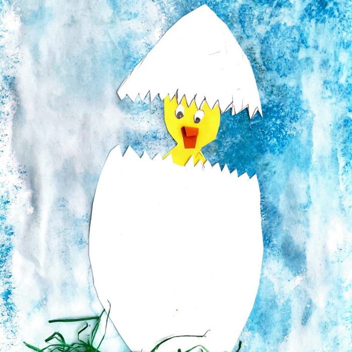 Küken schlüpft aus Ei vor blauem Hintergrund